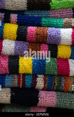 Plan macro mettant en évidence la texture du tissu éponge moelleux et les bandes de couleurs vives de serviettes de bain ou de plage empilées Banque D'Images