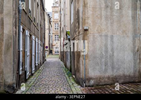 Aperçu d'une rue historique étroite pavée de pavés entre de grands bâtiments en pierre grise, avec des volets blancs fermés sur la gauche, ancien WE Banque D'Images