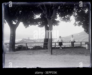 Eugène Trutat photographie des jeunes assis contre une barrière sur une esplanade surplombant une ville de la vallée du Rhin supérieur en Allemagne, capturant des points de vue élevés au-dessus du paysage fluvial et de l'environnement bâti environnant. Banque D'Images