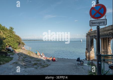 Friedrichshafen, Baden-Württemberg, Deutschland – Menschen genießen an einem warmen Sommerabend den Seezugang nahe der Uferpromenade in Friedrichshafen. IM Hintergrund sind Segelboote auf dem Bodensee und die Alpenkette am gegenüberliegenden Ufer zu sehen. 15.06.2026. Foto : Eibner-Pressefoto / Eky Eibner Banque D'Images