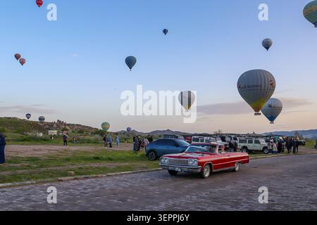 Cette superbe image capture les montgolfières vibrantes survolant les paysages uniques de la Cappadoce au lever du soleil. Banque D'Images