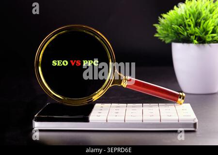 Une loupe se concentre sur les mots SEO et PPC au-dessus d'une calculatrice blanche. Une petite plante verte se trouve à proximité, ajoutant une touche de nature à la scène. Banque D'Images