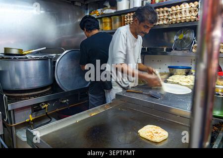 Chef préparant le pain plat traditionnel indien Roti Prata dans un stand de Street Food local animé dans le quartier de Little India, culture de Singapour Banque D'Images