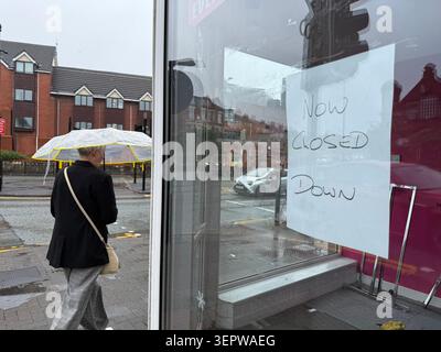 Ashton à Makerfield, Royaume-Uni. 16 juin 2026. Une femme traverse Ashton-in-Makerfield, la plus grande ville de la circonscription de Makerfield, sous la pluie. Jeudi, une élection partielle pour un siège au Parlement britannique aura lieu dans la circonscription de Makerfield, dans le nord-ouest de l'Angleterre. Le principal rival de Keir Starmer·au sein du parti, le maire de Manchester Andy Burnham, est candidat pour le Parti travailliste. Crédit : Patricia Bartos/dpa/Alamy Live News Banque D'Images