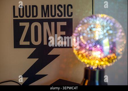Le panneau indique une zone de musique forte avec une boule lumineuse brillante pour les événements nocturnes à l'intérieur. Banque D'Images