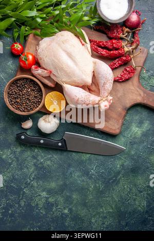 vue de dessus poulet cru frais avec des tomates rouges sur fond bleu foncé cuisine repas animal photo nourriture couleur poulet ferme Banque D'Images