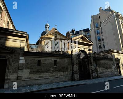 Paris, France - 14 mai 2026 : façade de l'église Saint-Joseph-des-Carmes classique ensoleillée et porte ornée à Paris, France avec ciel bleu et rue calme. Banque D'Images
