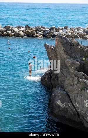Personnes sautant de rochers (tombstoning) dans la mer à Manarola, Cinque Terre, province de la Spezia, Ligurie, Italie du Nord. Banque D'Images