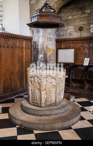 Les fonts baptismaux octogonaux en pierre du XIVe siècle sculptés avec des saints sous une couverture en bois à l'intérieur de l'église All Saints à Bakewell Banque D'Images