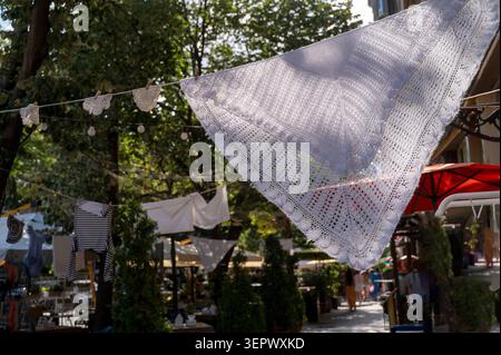 Mouchoirs en dentelle blanche suspendus à une corde dans une rue de la ville. Les textiles délicats créent une atmosphère romantique dans un café d'été. Concept de handcraf Banque D'Images