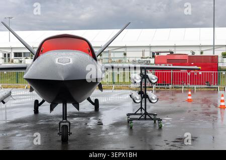 Vue de face du porte-missiles uav d'avion sans pilote avancé à l'extérieur de la chaussée mouillée ciel nuageux. Défense futuriste de surveillance de la technologie aérospatiale Banque D'Images