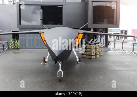 Vue de face du porte-missiles uav d'avion sans pilote avancé à l'extérieur de la chaussée mouillée ciel nuageux. Défense futuriste de surveillance de la technologie aérospatiale Banque D'Images