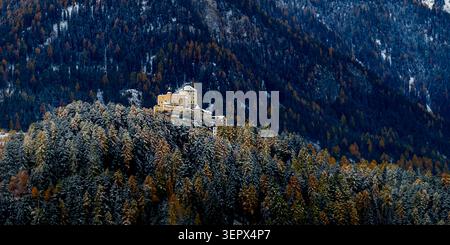 Vue aérienne du Schloss Tarasp perché sur une colline boisée avec des couleurs d'automne et de la neige légère à Scuol, Graubunden, Suisse. Banque D'Images