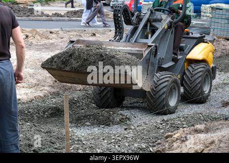 Un travailleur utilise une chargeuse, déplaçant du gravier et du béton pour la construction de routes. Kiev, Ukraine, 16 juin 2026 Banque D'Images