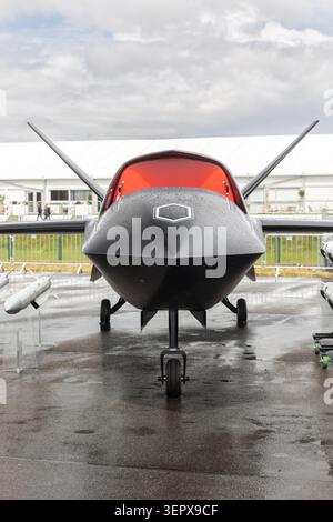 Vue de face du porte-missiles uav d'avion sans pilote avancé à l'extérieur de la chaussée mouillée ciel nuageux. Défense futuriste de surveillance de la technologie aérospatiale Banque D'Images