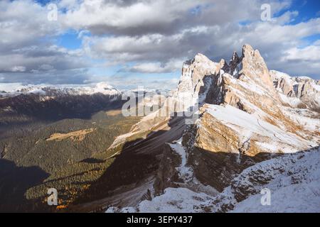 Crête de Seceda couverte de neige fraîche sous des nuages spectaculaires dans les Dolomites. Paysage alpin pittoresque avec des pics calcaires accidentés et lumière d'automne Banque D'Images
