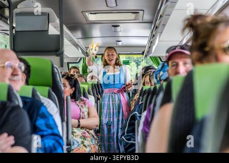 Guide touristique Stephanie Hinterbuchner dans un dirndl bleu chante avec les passagers dans un car bondé alors qu'il traverse le Salzkammergut, tout en tenant Goatherd, une chèvre en peluche. Photographie prise sur la Wolfgangseestraße en direction de Sankt Gilgen, Salzbourg, Autriche Banque D'Images