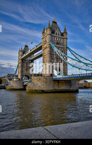 Vue en bas angle du Tower Bridge à Londres au-dessus de la Tamise, capturée par temps clair avec un ciel bleu et des nuages éparpillés. Banque D'Images
