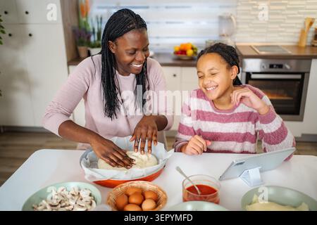 Mère et fille faisant la pizza ensemble dans la cuisine Banque D'Images