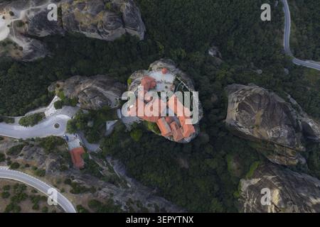 Vue aérienne du monastère Saint de Rousanou perché sur un pilier rocheux escarpé entouré de forêts verdoyantes et de routes sinueuses dans les Météores, Trikala, G. Banque D'Images