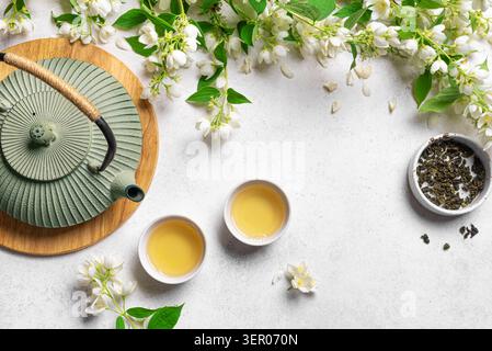 Thé vert au jasmin dans une théière et des tasses à thé sur fond blanc, vue de dessus, espace de copie. Thé naturel au jasmin et fleurs. Banque D'Images