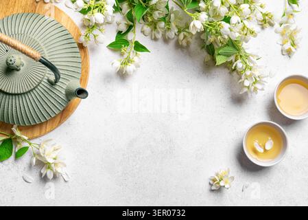 Thé vert japonais au jasmin dans une théière en fonte et des tasses à thé sur fond blanc, vue de dessus, espace de copie. Thé naturel au jasmin et fleurs, modèle f Banque D'Images
