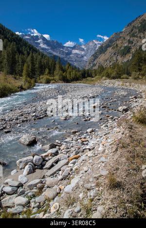 Rivière alpine coulant à travers une vallée avec des montagnes enneigées Banque D'Images
