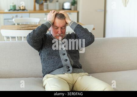 Maux de tête. Malheureux homme âgé d'âge moyen souffrant de maux de tête malade frottant les tempes à la maison. Vieux grand-père aîné mature touchant les temples éprouvant du stress. Homme sentant mal à la tête Banque D'Images