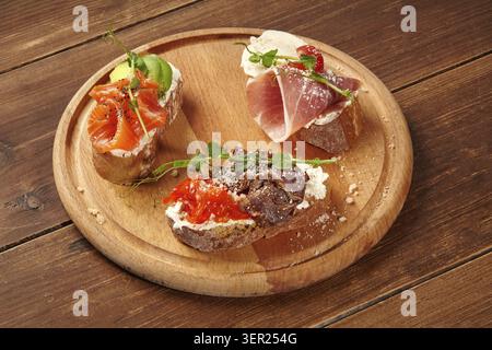 Variété de bruschetta avec différentes garnitures servies sur une planche de bois, mettant en valeur des hors-d'œuvre gastronomiques Banque D'Images