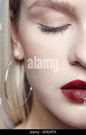 Portrait de belle jeune femme blonde avec boucles d'oreilles. Femelle blonde avec les yeux fermés Banque D'Images