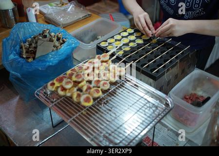 Vendeur de nourriture de rue préparant des brochettes d'œufs de caille sur une poêle de cuisson à un marché nocturne à Melaka, en Malaisie. Banque D'Images