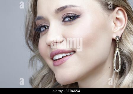 Portrait de beauté d'une jeune femme blonde souriante. Femme portant des boucles d'oreilles avec des strass Banque D'Images