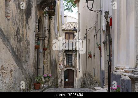 Ruelle étroite avec des maisons traditionnelles en pierre, des balcons et des fleurs en pot dans le centre historique de Gerace, parc national d'Aspromonte, Calabre Sud Banque D'Images