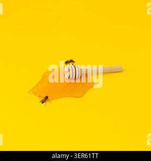Mise en page créative avec du miel naturel frais, un plongeur de miel et des abeilles de miel volant autour sur fond jaune. Concept de nature minimale. Nourriture biologique tendance Banque D'Images