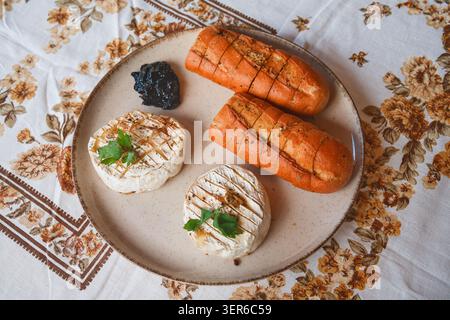 Camembert cuit au four avec baguette aux herbes et confiture de myrtilles Banque D'Images
