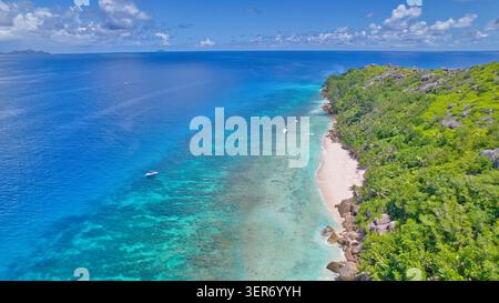 Vue aérienne par drone de Little Sister Island, Seychelles, montrant un bateau d'excursion ancré dans une eau turquoise à côté d'une plage de sable blanc Banque D'Images