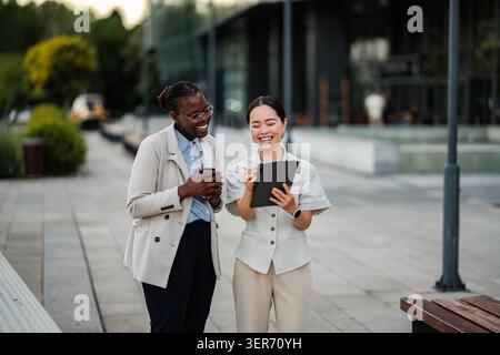 Diverses femmes d'affaires souriantes regardant la tablette numérique en extérieur Banque D'Images