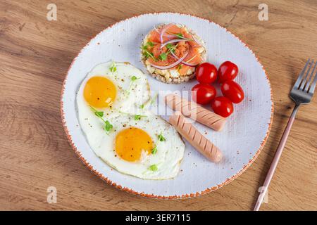 Oeufs frits avec saucisse, tomates cerises et pain de sarrasin avec saumon Banque D'Images