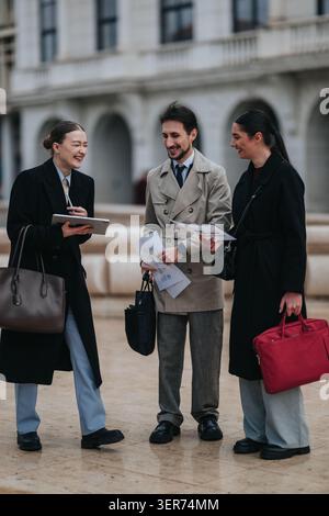 Collègues d'affaires discutant et riant à l'extérieur avec des documents et des porte-documents sur la place de la ville Banque D'Images