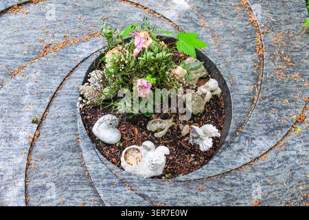 Conception de tombe circulaire avec statues d'ange en pierre et bouquet de roses roses sur un parterre de granit fleuri vue de dessus Banque D'Images