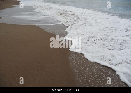 Vagues se brisant sur le sable à la plage pendant la journée Banque D'Images