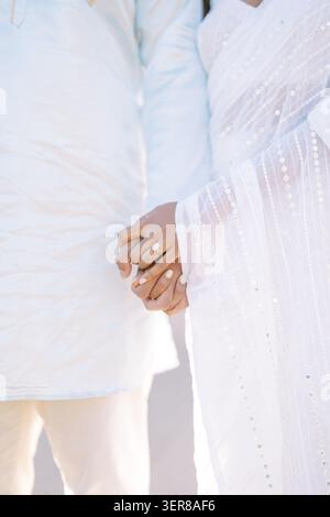 Gros plan d'un couple tenant la main en tenue blanche traditionnelle Banque D'Images