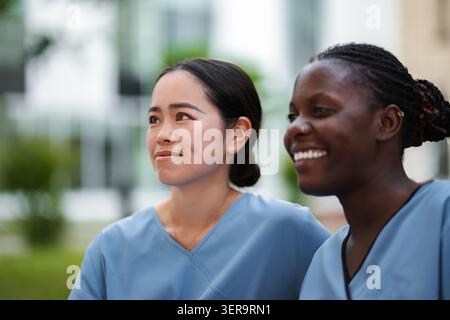 Diverses travailleuses de la santé souriantes, regardant loin avec espoir Banque D'Images