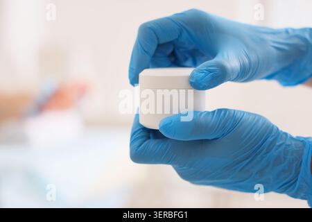 Esthéticienne avec pot de crème et jeune homme couché sur le canapé dans le salon de spa, gros plan Banque D'Images