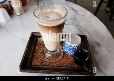 Café latte glacé et café noir chaud avec du thé dans un plateau tissé sur une table dans un café thaïlandais traditionnel Banque D'Images