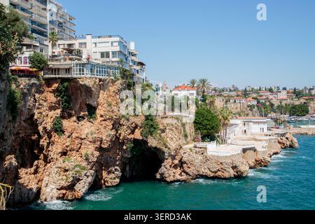 Les maisons modernes à plusieurs étages se dressent au bord de falaises de calcaire abruptes avec de grandes grottes naturelles et des niches d'érosion juste au-dessus de la surface de la mer. Été Banque D'Images