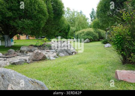 Beau jardin de rocaille avec des pierres naturelles décoratives sur une pelouse herbeuse verte. Aménagement paysager professionnel avec lit de ruisseau sec avec de grands rochers Banque D'Images