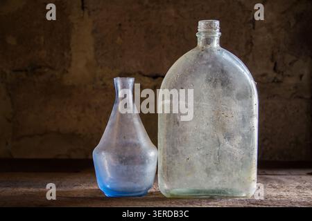 Bouteilles vintage poussiéreuses. Verrerie antique sur une ancienne étagère. Deux bouteilles en verre. Banque D'Images