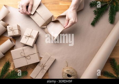 Femme pliant le papier kraft autour de la boîte cadeau de Noël Banque D'Images