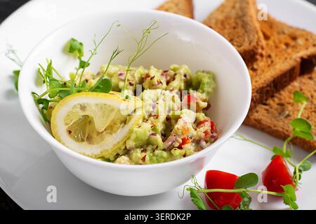 Trempette saine d'avocat dans un bol avec toast et Microgreens en gros plan Banque D'Images